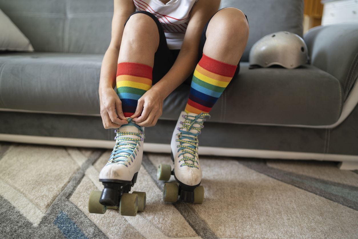 Close up of someone is tying the laces on roller skates over rainbow socks